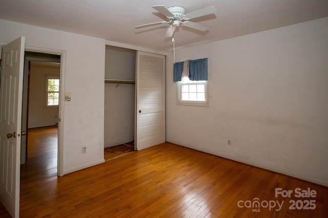 unfurnished bedroom with a closet, wood-type flooring, and multiple windows