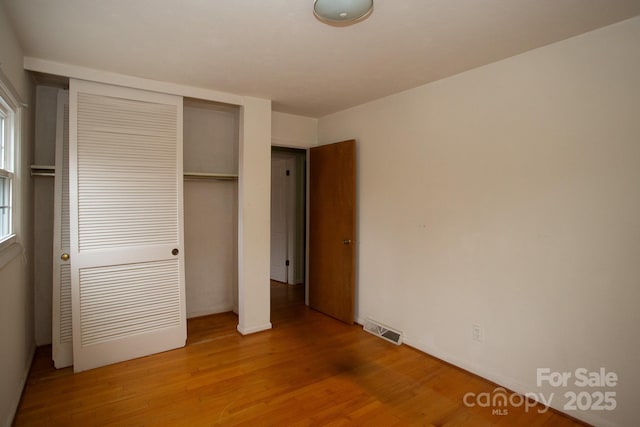 unfurnished bedroom with a closet and light wood-type flooring