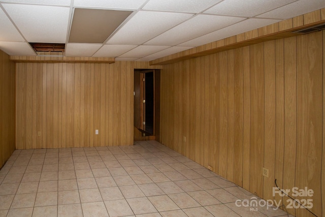 spare room with a paneled ceiling and wood walls