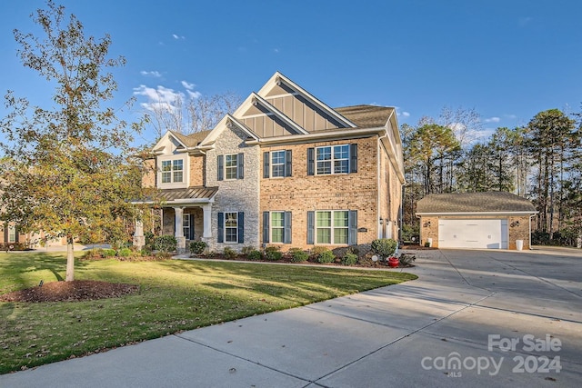 craftsman inspired home featuring a garage, an outbuilding, and a front lawn