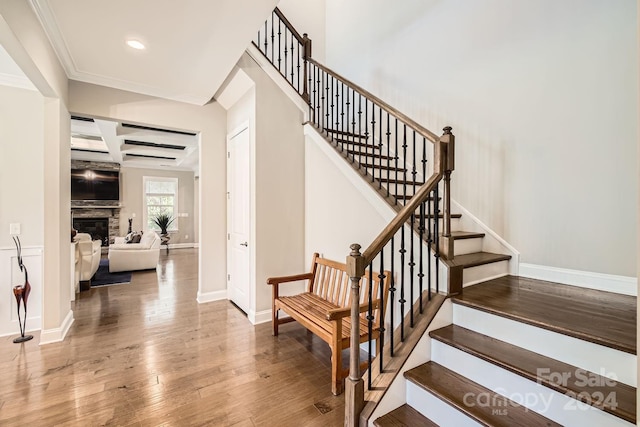 staircase with hardwood / wood-style flooring, ornamental molding, and coffered ceiling