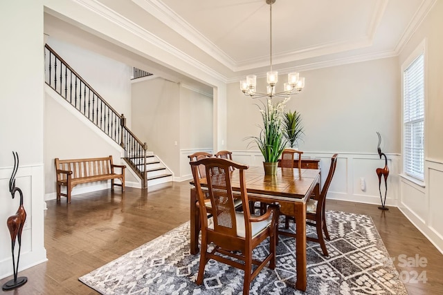 dining area featuring a tray ceiling, ornamental molding, dark hardwood / wood-style floors, and a notable chandelier