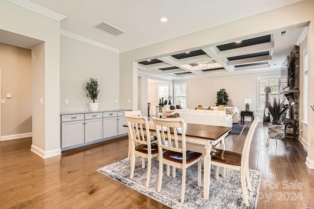 dining space featuring beam ceiling, crown molding, coffered ceiling, and light wood-type flooring