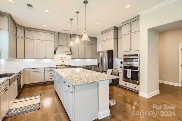 kitchen with light stone countertops, a center island, stainless steel appliances, a breakfast bar, and custom exhaust hood