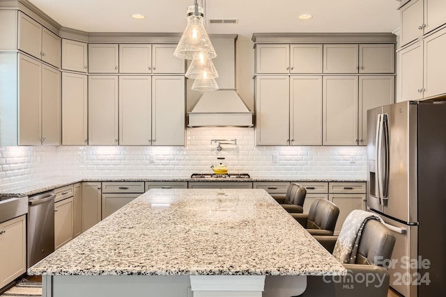 kitchen with light stone counters, stainless steel appliances, decorative light fixtures, a kitchen island, and a breakfast bar area