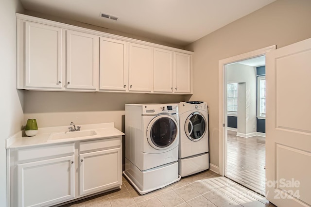 washroom with cabinets, light tile patterned floors, sink, and washing machine and dryer