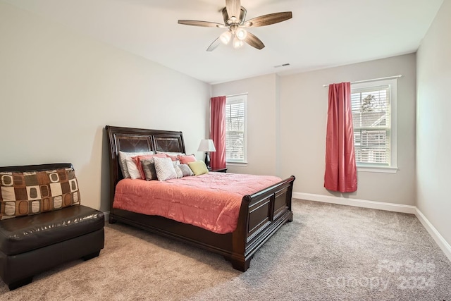 bedroom featuring multiple windows, light colored carpet, and ceiling fan