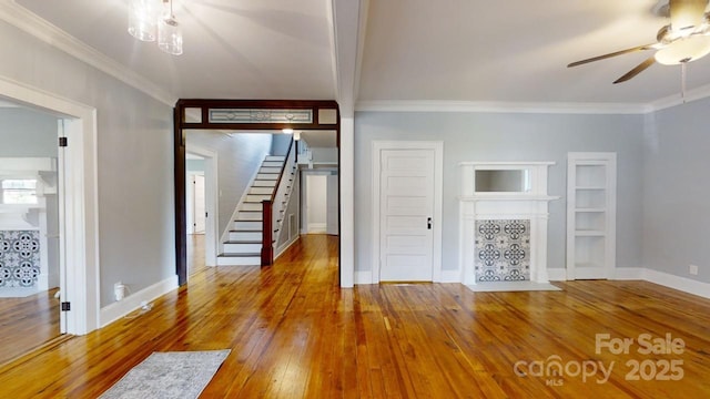 unfurnished living room featuring hardwood / wood-style flooring, ceiling fan, and crown molding