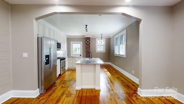 kitchen featuring a center island, light stone countertops, light wood-type flooring, appliances with stainless steel finishes, and white cabinetry