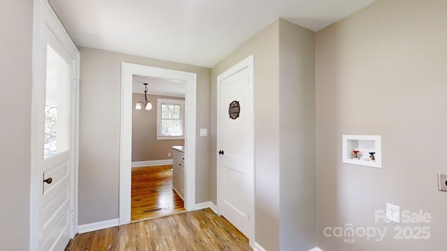 clothes washing area featuring a chandelier, washer hookup, and light hardwood / wood-style floors