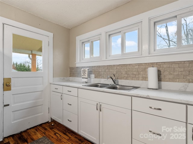 kitchen featuring sink, dark wood-type flooring, white cabinetry, backsplash, and a textured ceiling