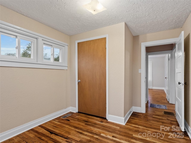 hallway featuring wood-type flooring and a textured ceiling