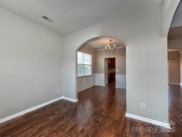 spare room with dark hardwood / wood-style floors and an inviting chandelier