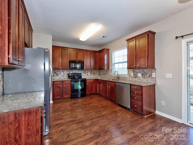 kitchen with light stone countertops, tasteful backsplash, dark wood-type flooring, sink, and black appliances