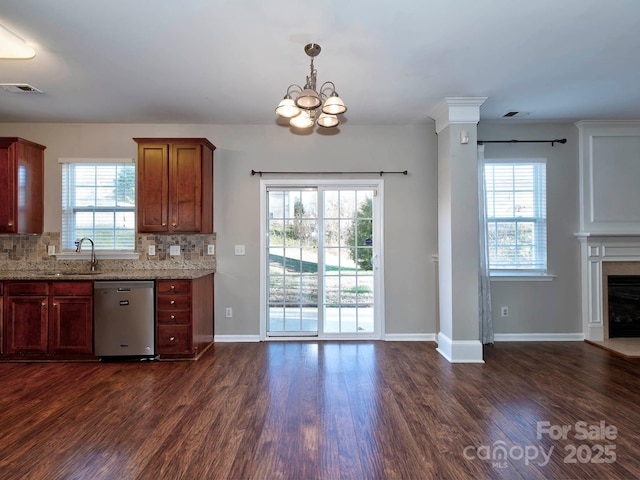 kitchen featuring tasteful backsplash, light stone counters, stainless steel dishwasher, a healthy amount of sunlight, and sink