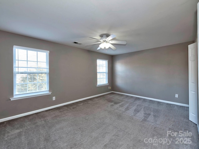 empty room featuring ceiling fan and dark carpet