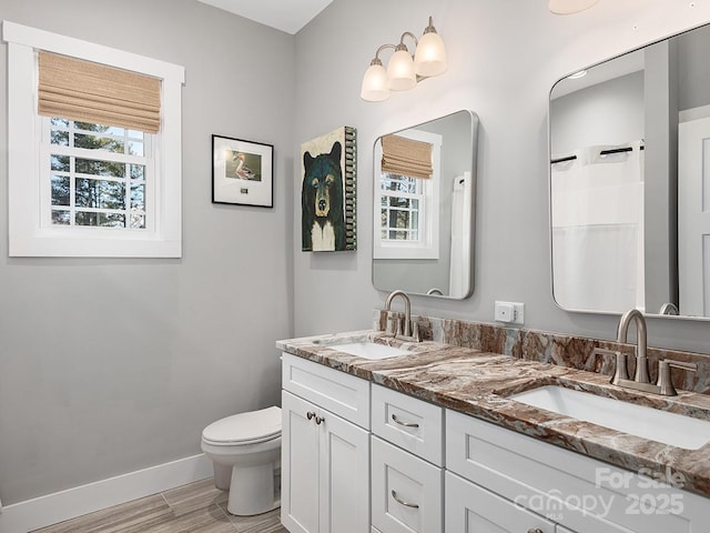 bathroom featuring hardwood / wood-style flooring, plenty of natural light, vanity, and toilet