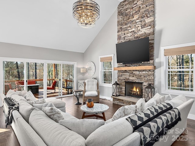 living room featuring a fireplace, high vaulted ceiling, dark wood-type flooring, and an inviting chandelier