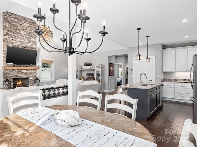 dining room featuring a fireplace, sink, dark wood-type flooring, and an inviting chandelier