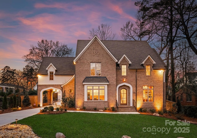 traditional-style home featuring a lawn, brick siding, driveway, and a shingled roof