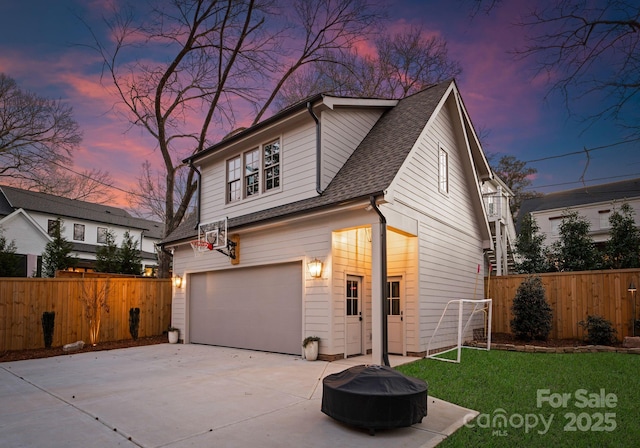 property exterior at dusk featuring fence, a garage, driveway, and a shingled roof