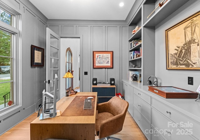 office area with a decorative wall and light wood-type flooring