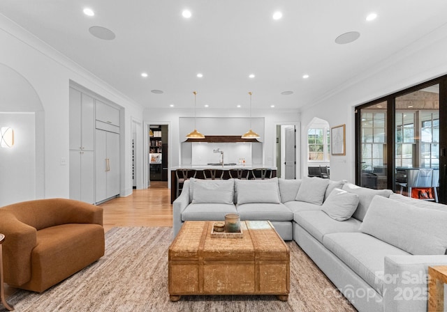 living room featuring recessed lighting, arched walkways, and ornamental molding