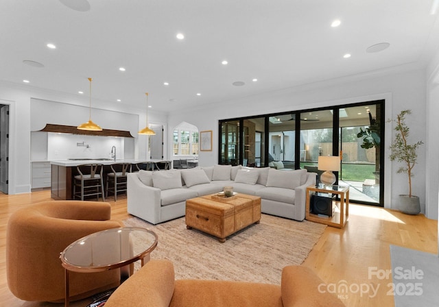 living area featuring crown molding, recessed lighting, and light wood-style floors