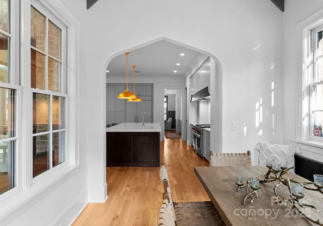 dining area featuring recessed lighting, arched walkways, light wood-style floors, and crown molding