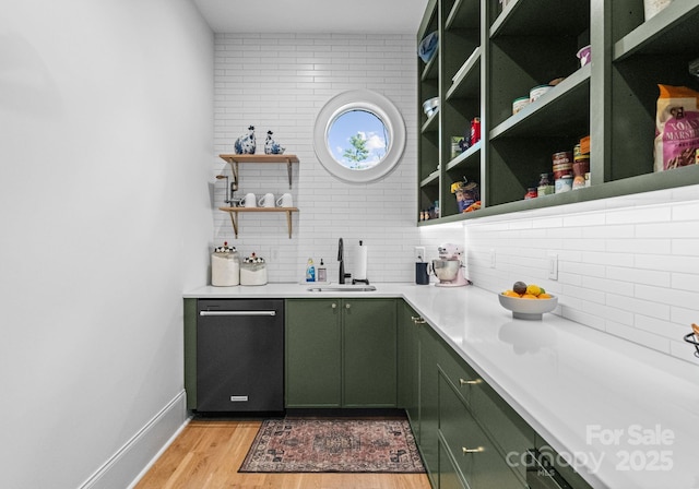 bar featuring stainless steel dishwasher, backsplash, sink, and green cabinetry