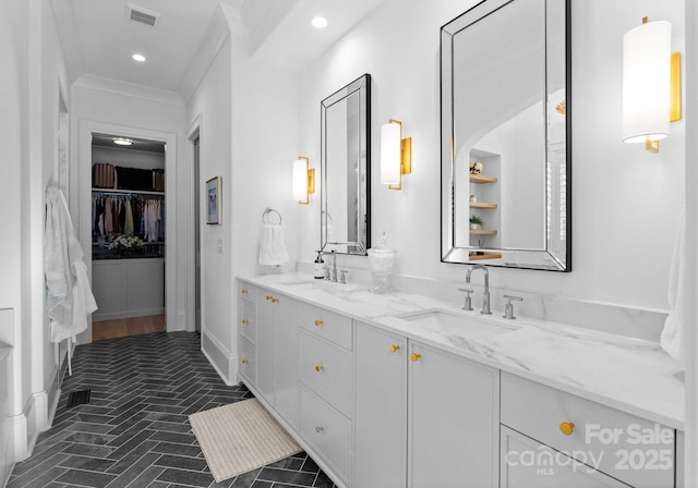 full bathroom featuring double vanity, visible vents, a walk in closet, and a sink