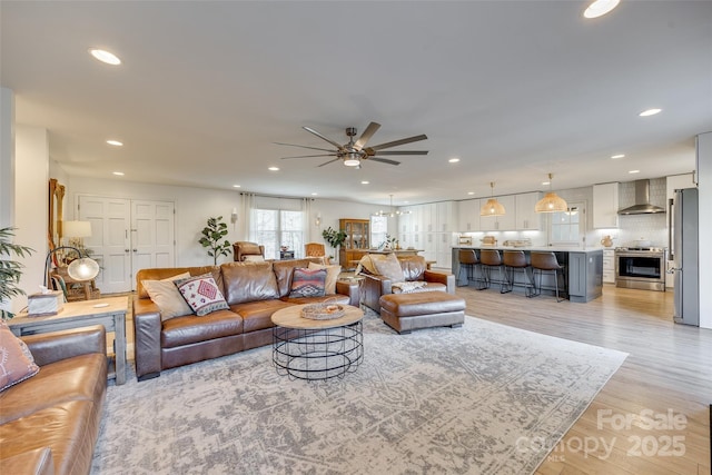 living room featuring ceiling fan with notable chandelier and light hardwood / wood-style floors