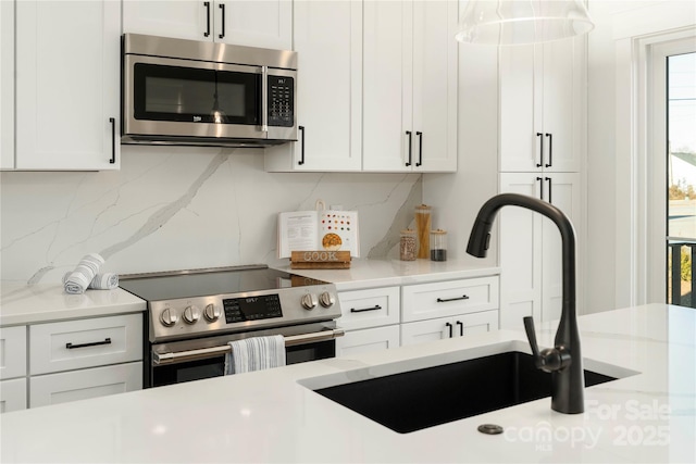 kitchen featuring decorative backsplash, light stone countertops, stainless steel appliances, sink, and white cabinets