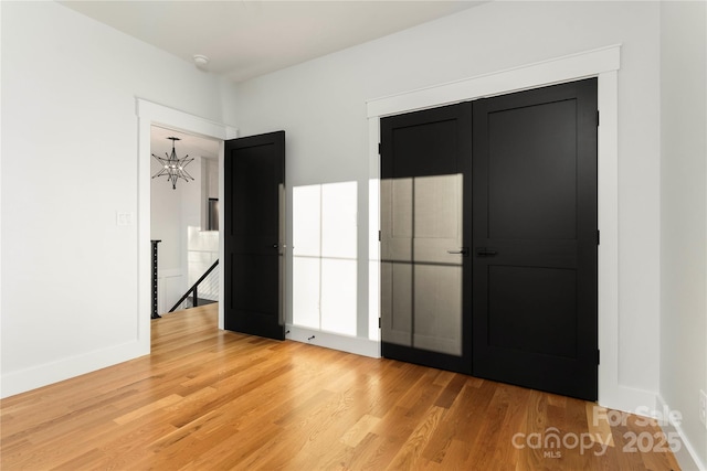 unfurnished bedroom with a closet, a notable chandelier, and hardwood / wood-style flooring