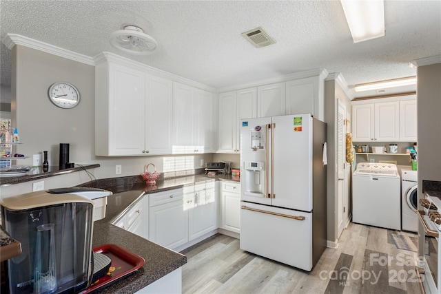 kitchen featuring white fridge with ice dispenser, washing machine and dryer, crown molding, a textured ceiling, and white cabinets