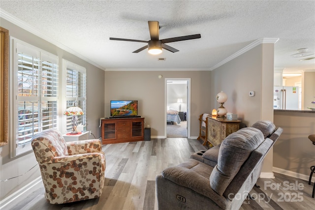 living room with crown molding, ceiling fan, a textured ceiling, and light wood-type flooring