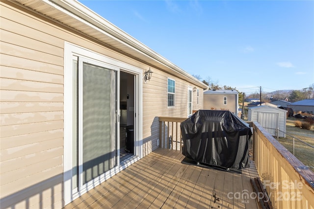 wooden terrace with area for grilling and a shed