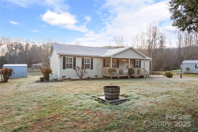 single story home featuring covered porch, a front lawn, and a storage unit