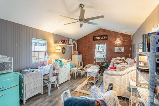 bedroom featuring hardwood / wood-style flooring, ceiling fan, brick wall, and vaulted ceiling