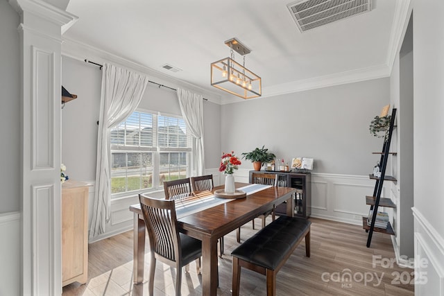 dining space featuring a notable chandelier, light wood-type flooring, and ornamental molding