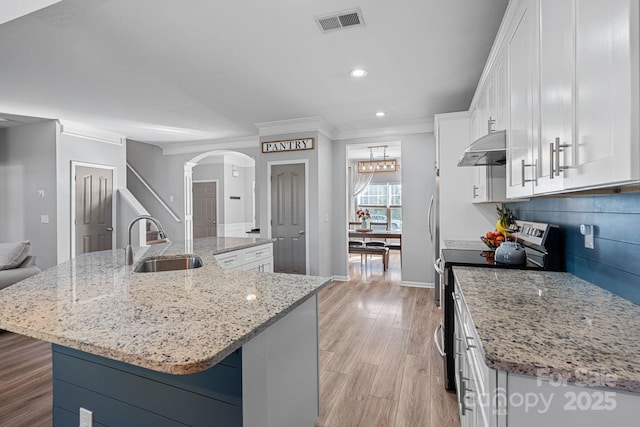 kitchen featuring light stone countertops, a kitchen island with sink, white cabinetry, stainless steel range with electric stovetop, and sink