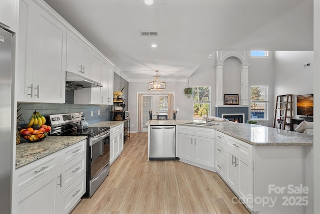 kitchen with appliances with stainless steel finishes, hanging light fixtures, decorative backsplash, white cabinets, and sink