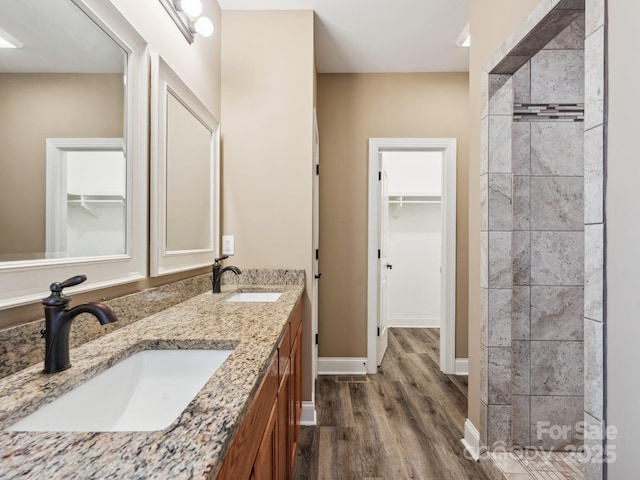 bathroom featuring tiled shower, wood-type flooring, and vanity