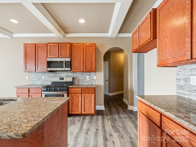 kitchen featuring stainless steel appliances, tasteful backsplash, light stone counters, light hardwood / wood-style floors, and ornamental molding