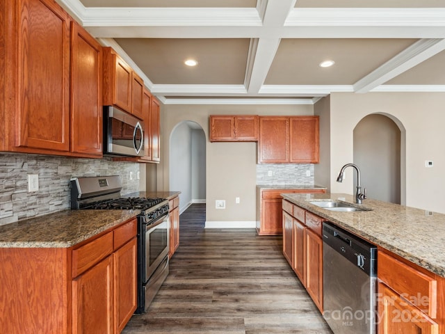 kitchen featuring light stone countertops, sink, dark wood-type flooring, stainless steel appliances, and decorative backsplash