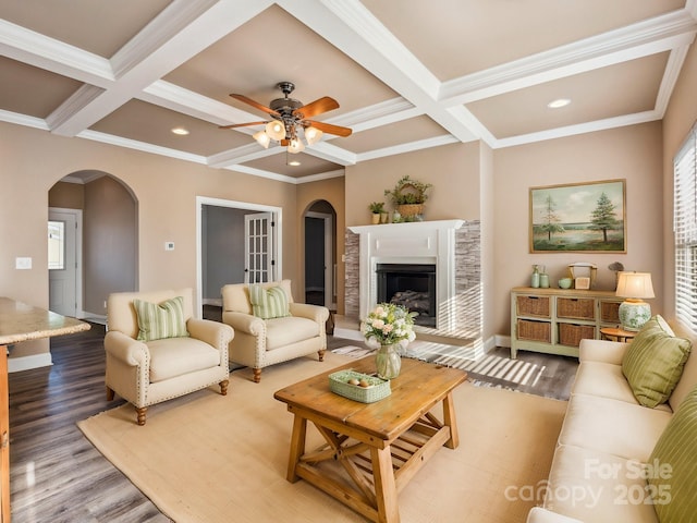 living room featuring ceiling fan, coffered ceiling, beamed ceiling, hardwood / wood-style floors, and ornamental molding