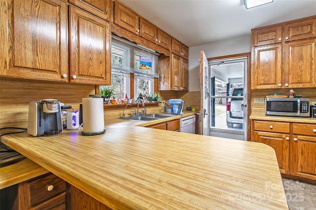 kitchen with wood counters, dishwasher, kitchen peninsula, and sink