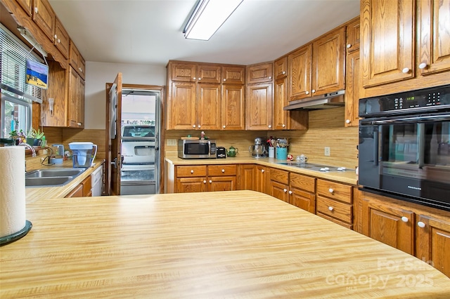 kitchen featuring kitchen peninsula, decorative backsplash, white dishwasher, stovetop, and sink