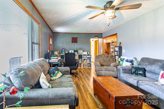 living room featuring wood-type flooring, a textured ceiling, crown molding, and ceiling fan