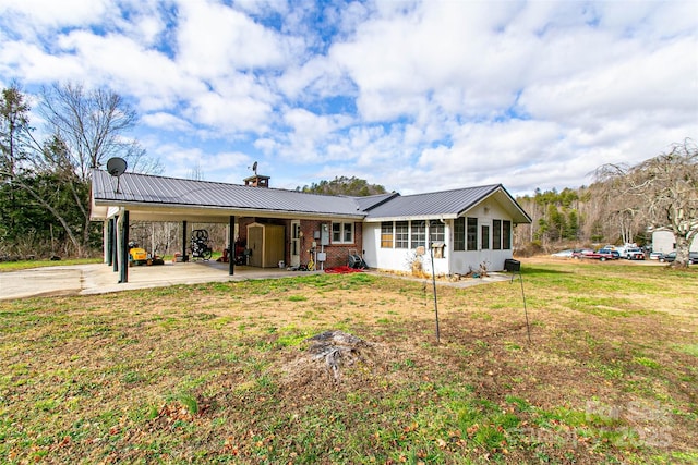 view of front of property with a sunroom, metal roof, an attached carport, a front lawn, and brick siding